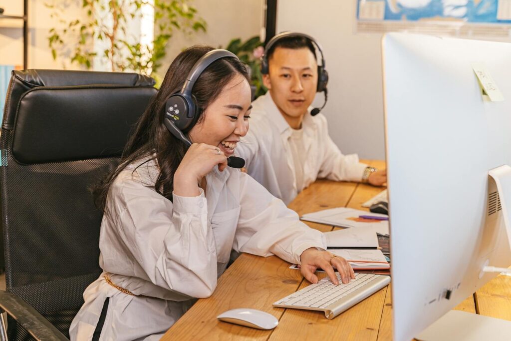 Two call center agents working together, focused and engaged at their desks, communicating via headsets.